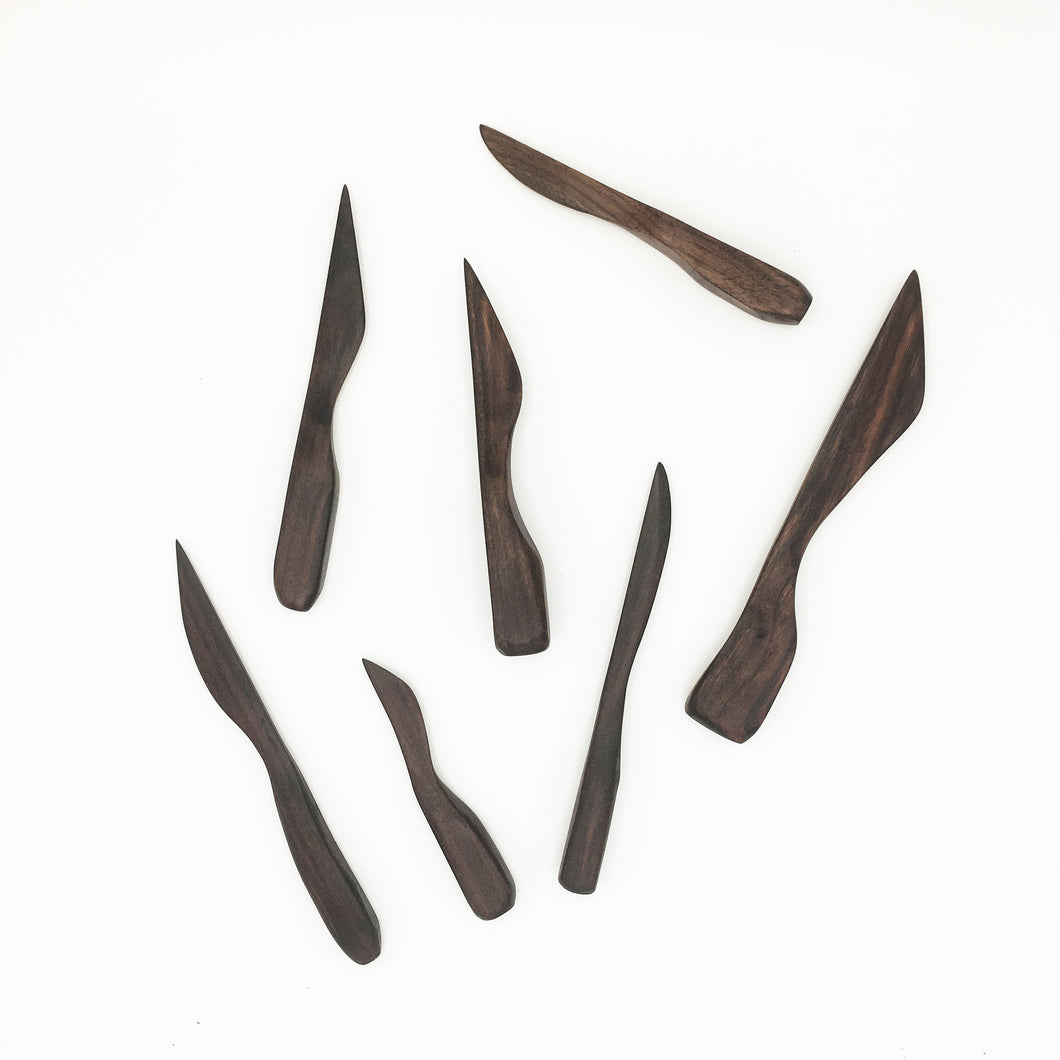 Several Walnut Nifty Spreading Knives of varying sizes ans shapes on white background. 